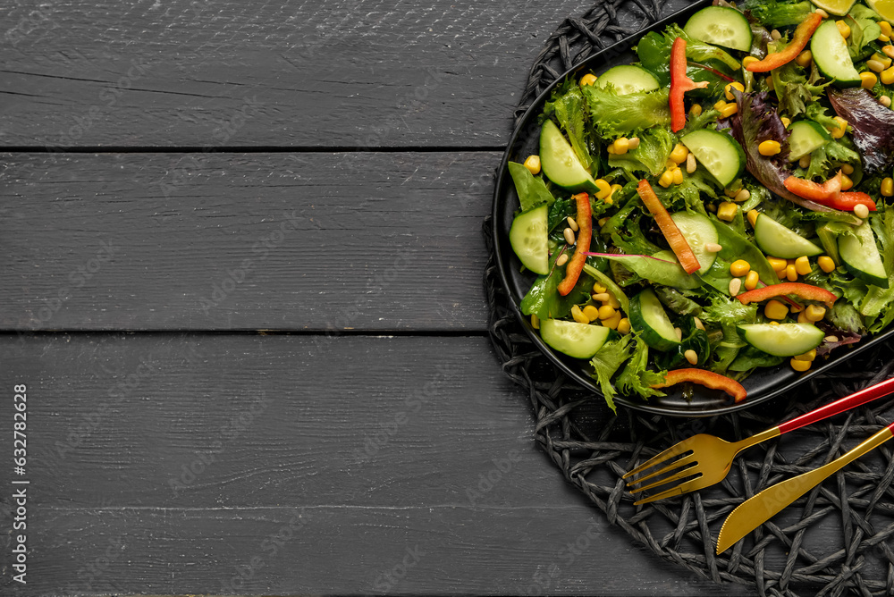 Plate with fresh vegetable salad on black wooden background