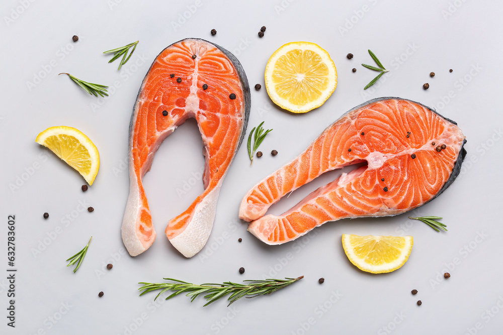 Raw salmon steaks and different spices on grey background