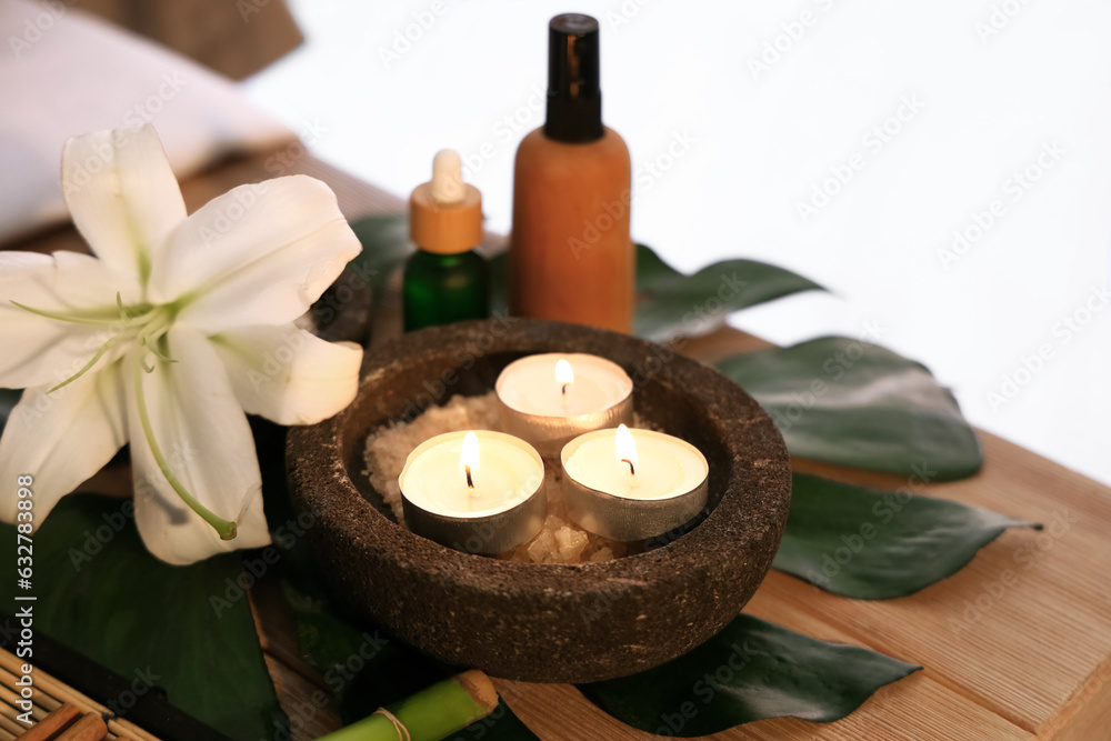 Burning candles, flower and essential oil on table in spa salon