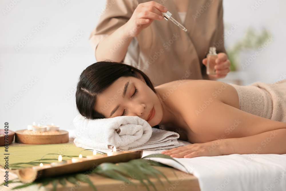 Pretty young Asian woman relaxing in spa salon