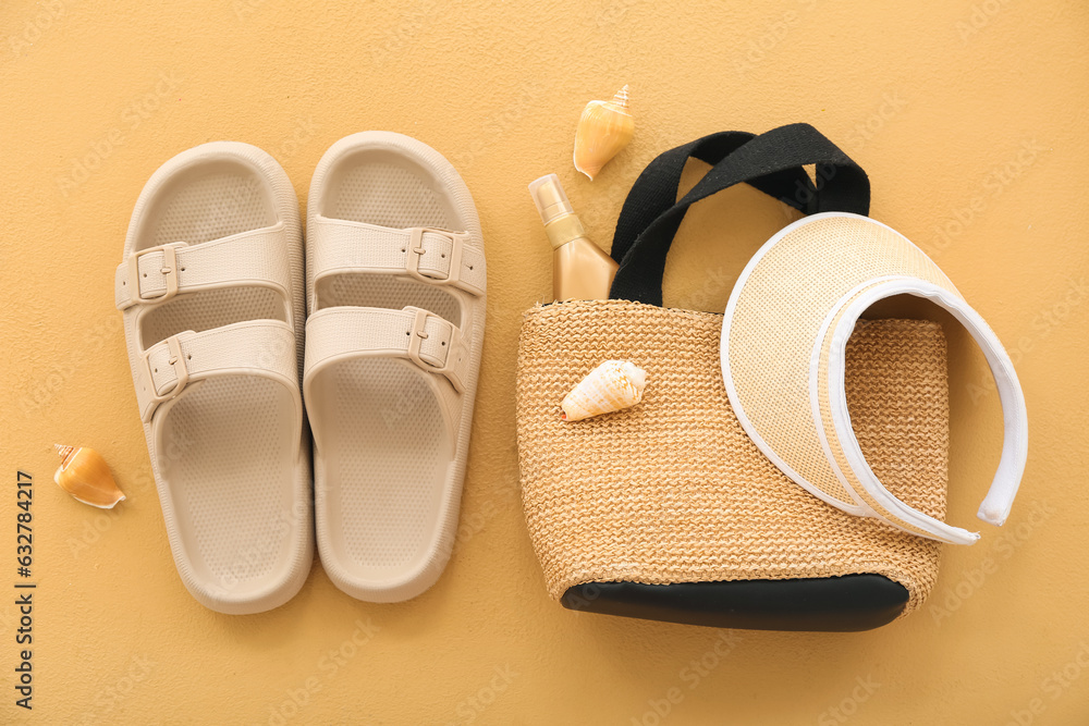 Pair of flip flops with beach accessories and shells on beige background