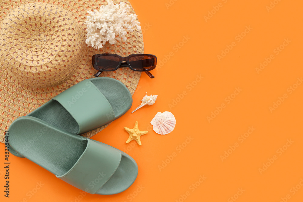 Pair of green flip flops with straw hat and coral on orange background