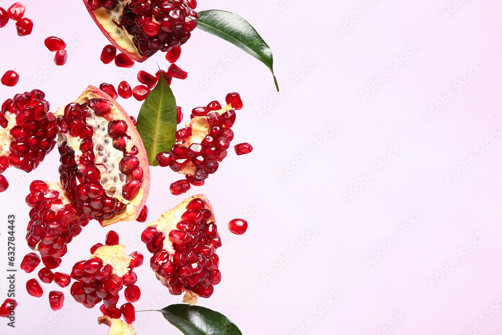 Flying fresh pomegranates with seeds and leaves on lilac background