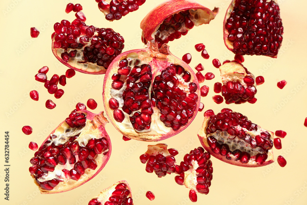 Flying fresh pomegranates with seeds on yellow background