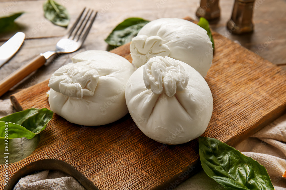 Board of tasty Burrata cheese with basil on wooden background