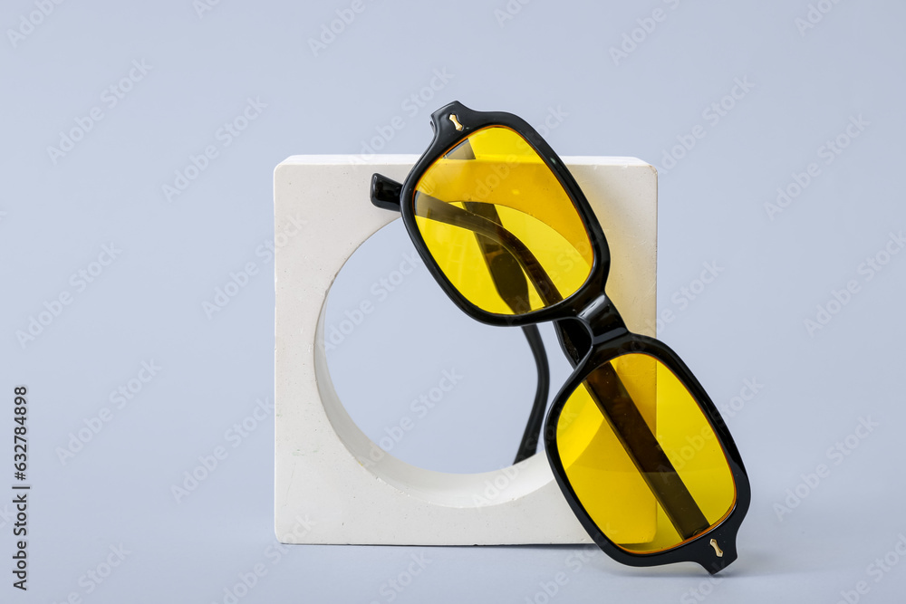 Decorative podium with stylish sunglasses on blue background