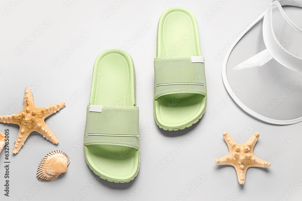 Female stylish flip flops with cap and starfishes on grey background