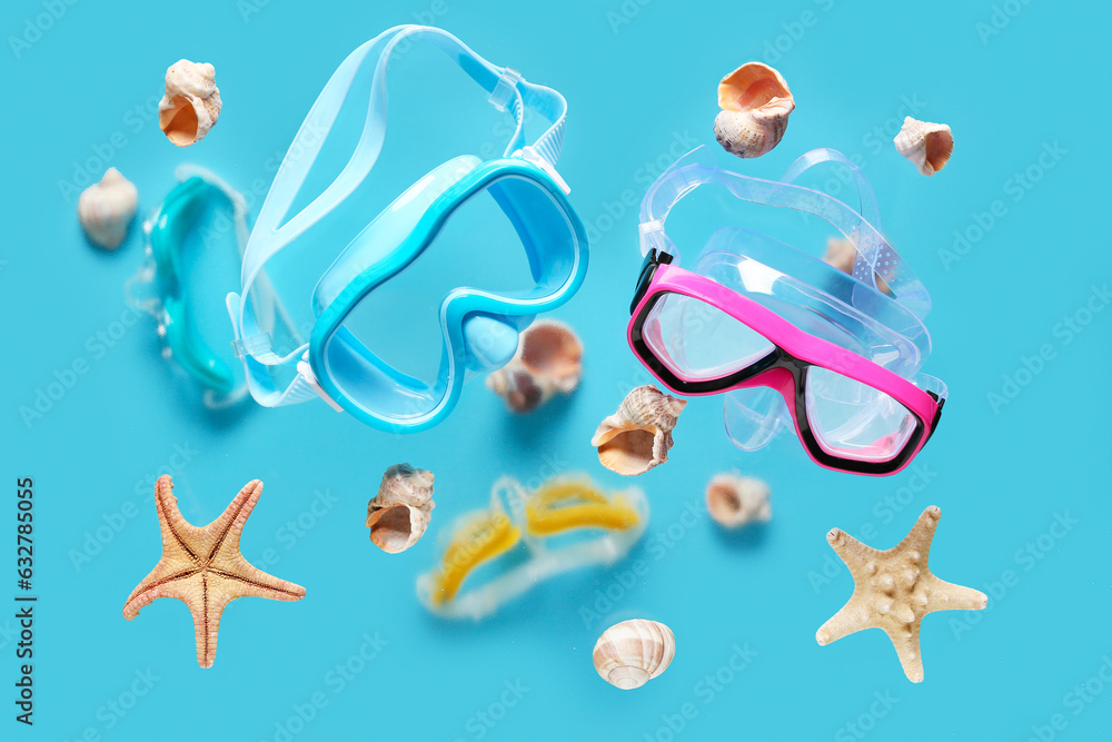 Flying snorkeling masks, seashells and starfishes on color background