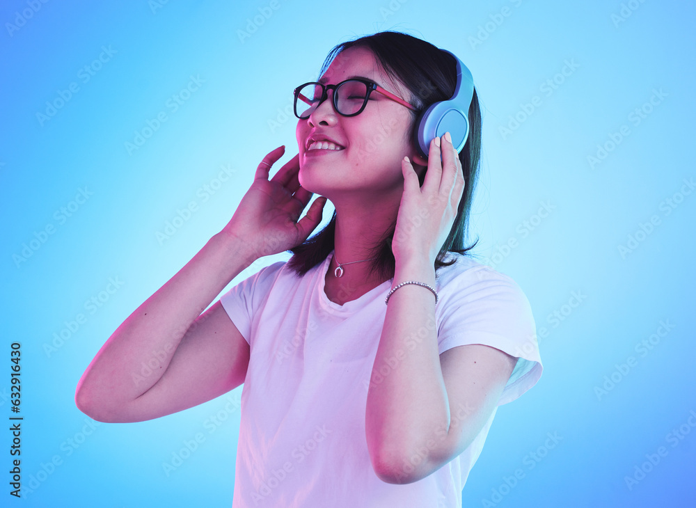 Young woman, student and headphones for listening, audio streaming and happy subscription on blue ba