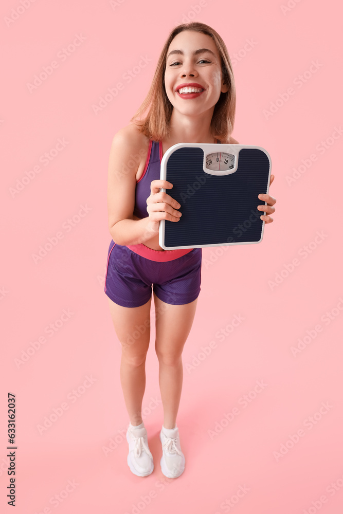 Sporty young woman with scales on pink background