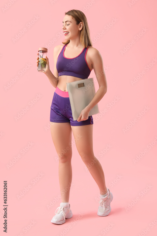 Sporty young woman with scales and bottle of water on pink background