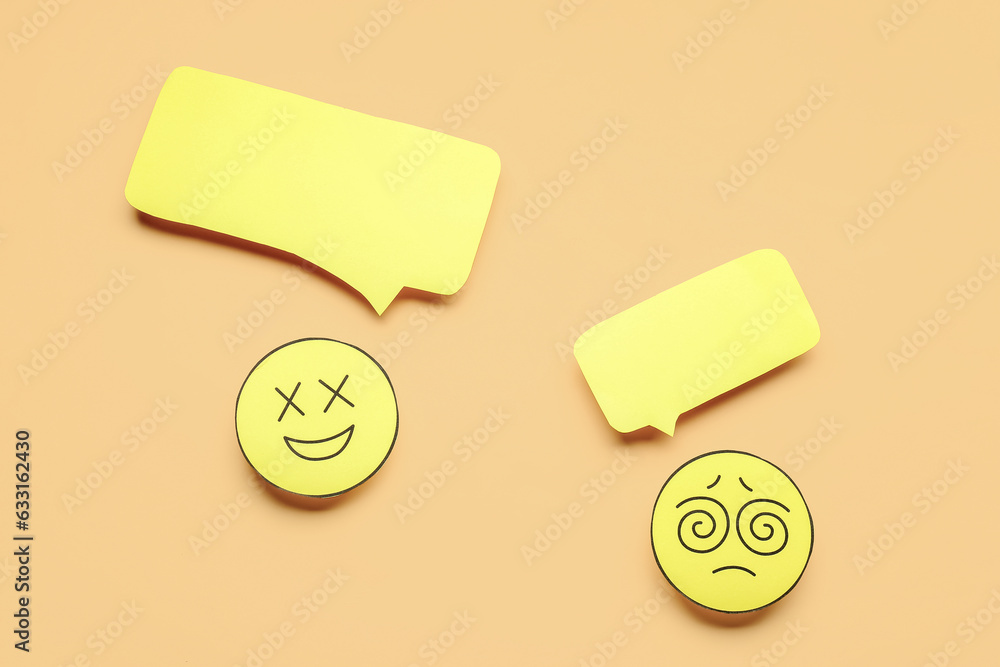 Paper faces with blank speech bubbles on beige background