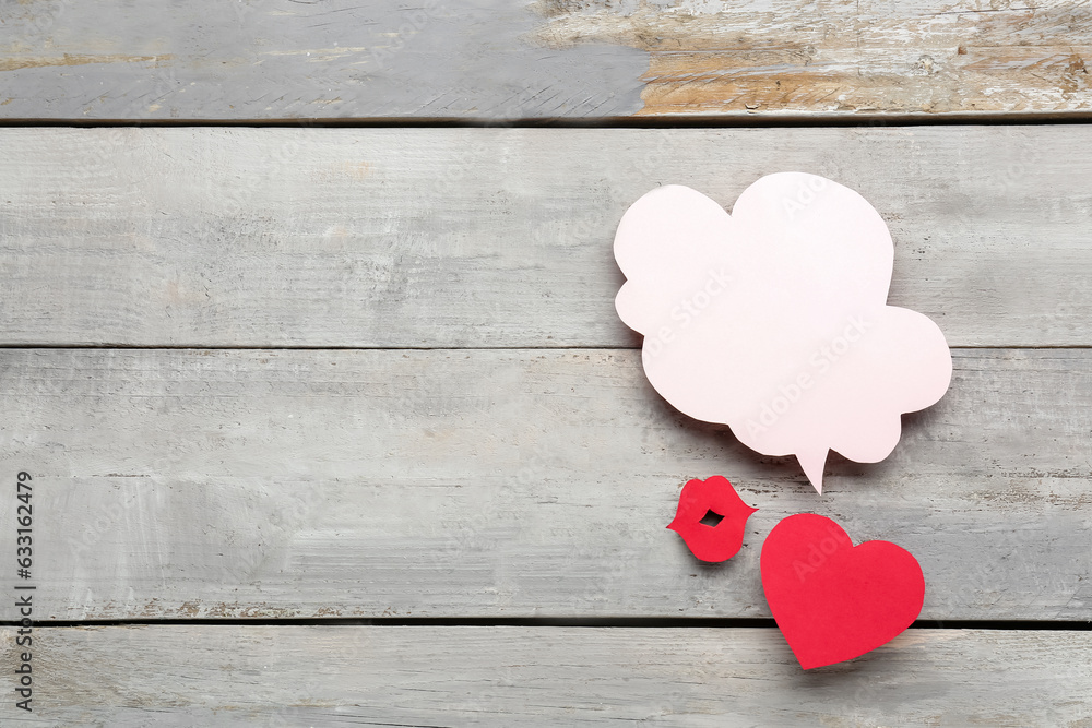 Paper lips and heart with blank speech bubble on grey wooden background