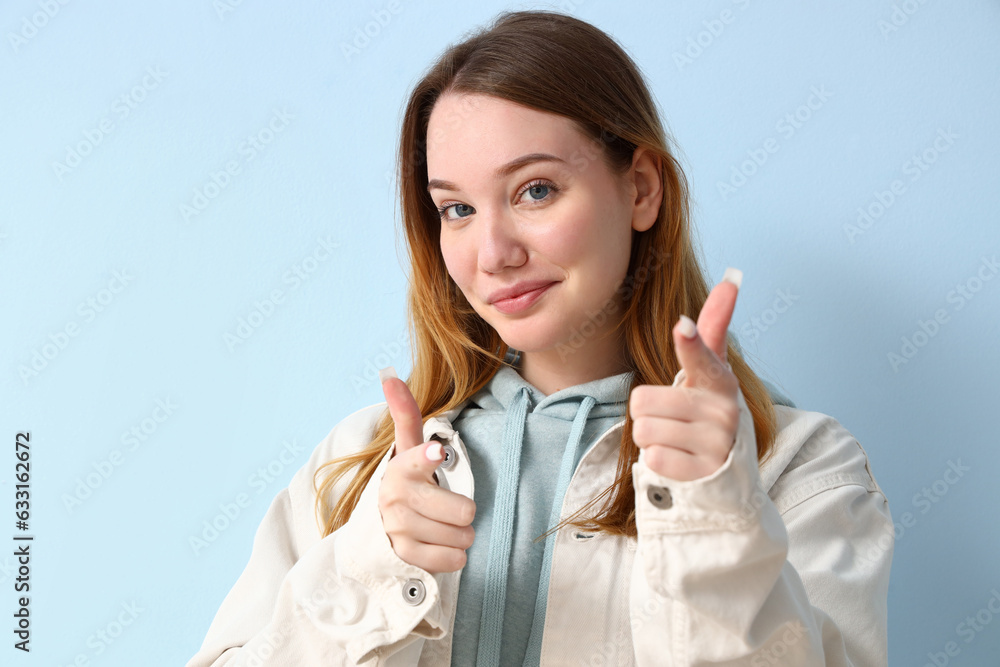 Beautiful young woman pointing at viewer on blue background, closeup