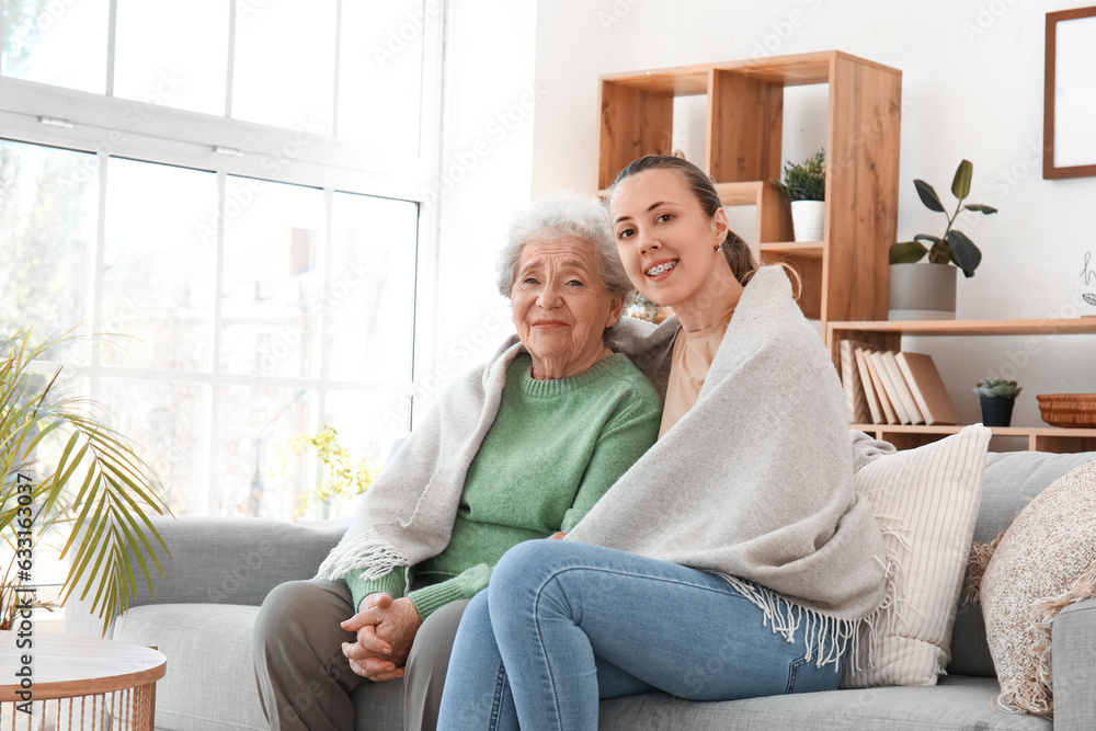 Senior woman with her granddaughter and plaid at home