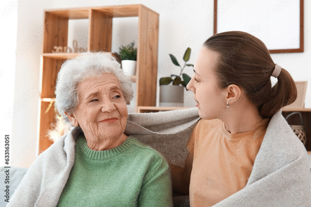 Senior woman with her granddaughter and plaid at home, closeup