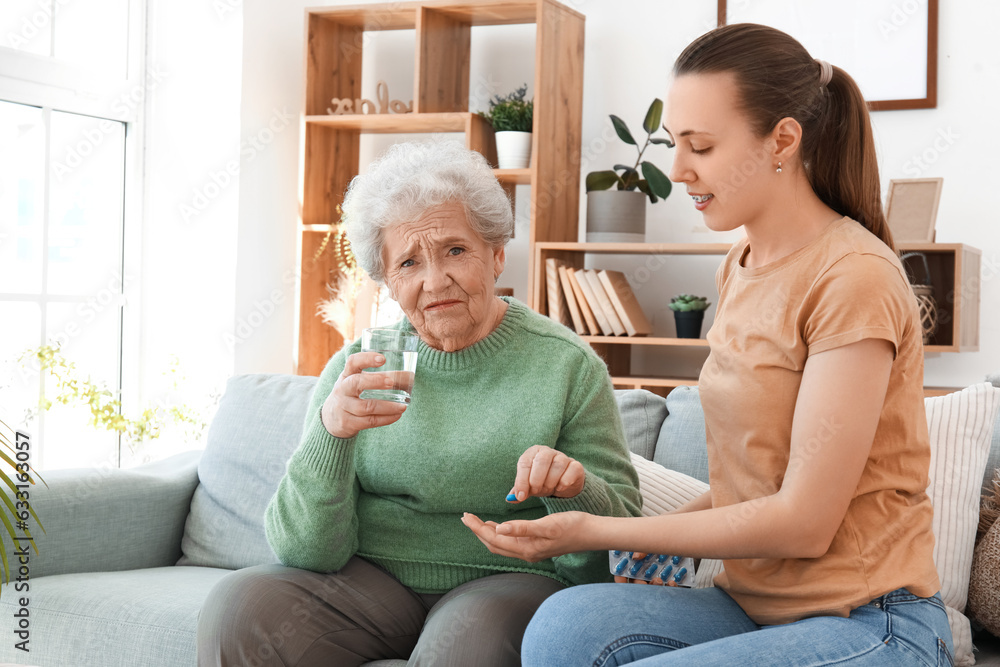 Senior woman with her granddaughter taking pills at home