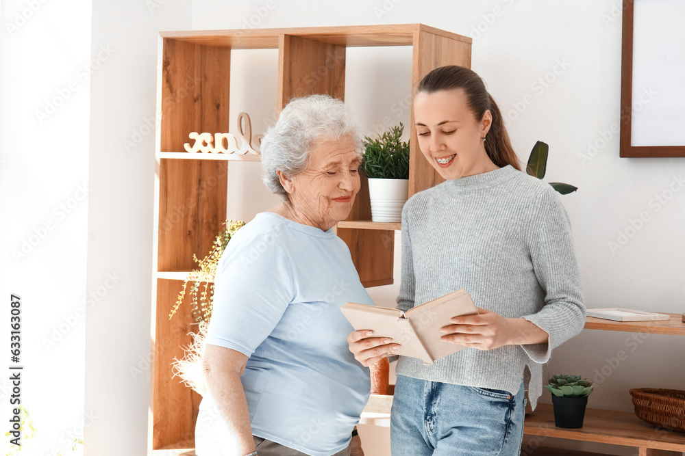 Senior woman with her granddaughter reading book at home