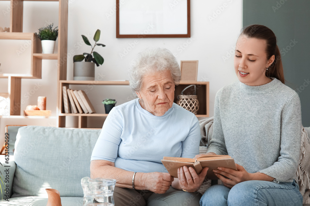 Senior woman with her granddaughter reading book at home