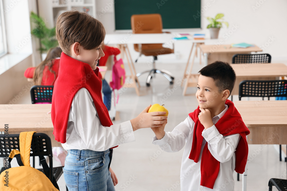 Cute little boys with apple in classroom