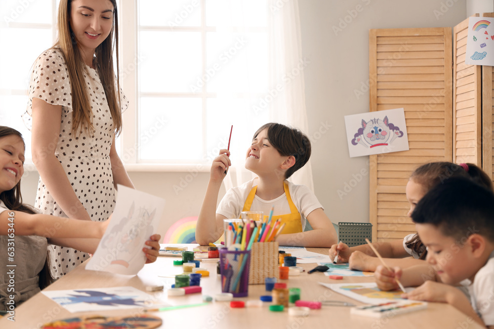 Little pupils drawing with teacher in art class