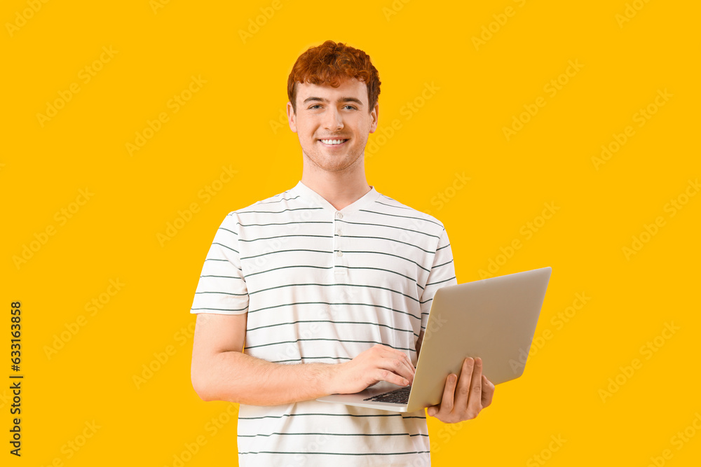 Male programmer working with laptop on yellow background