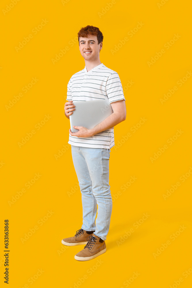 Male programmer with laptop on yellow background