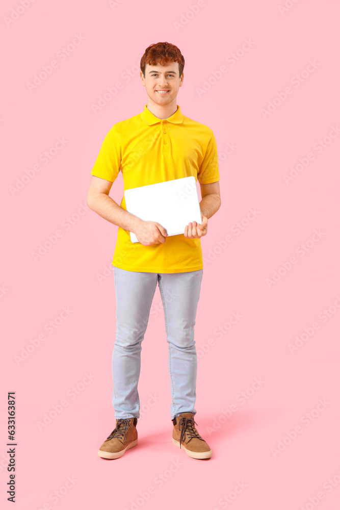 Male programmer with laptop on pink background