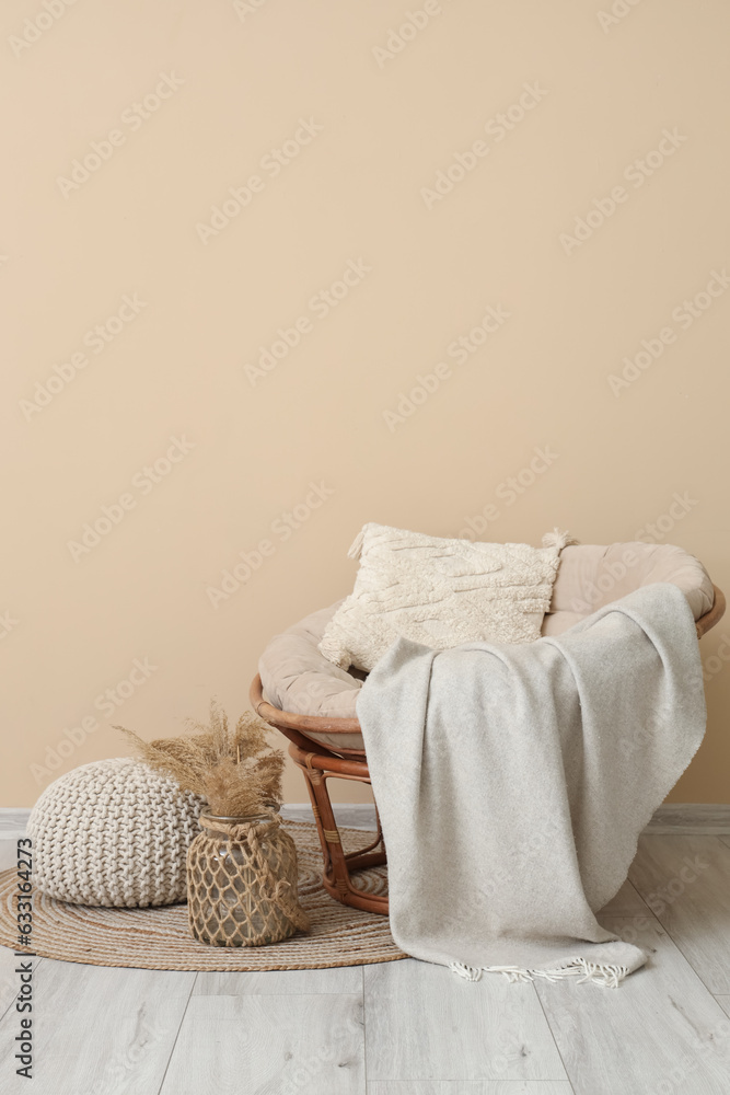 Interior of living room with plaid on armchair and pouf