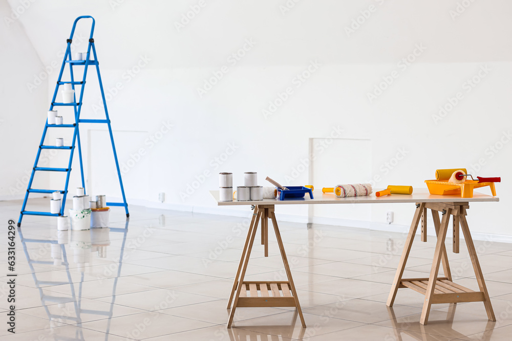 Table with paint cans and rollers in room