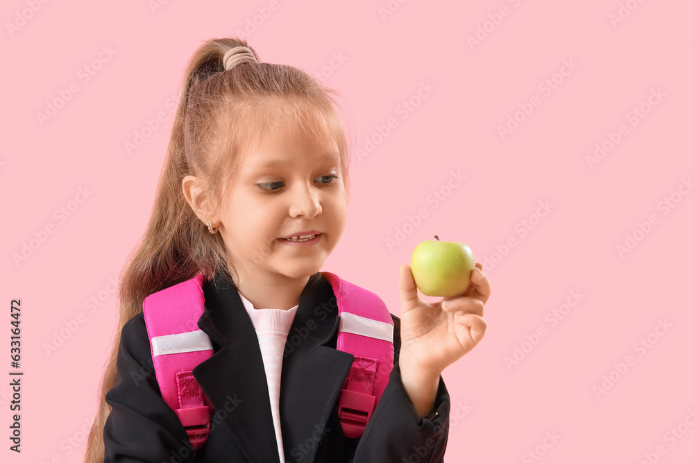 Little schoolgirl with apple on pink background