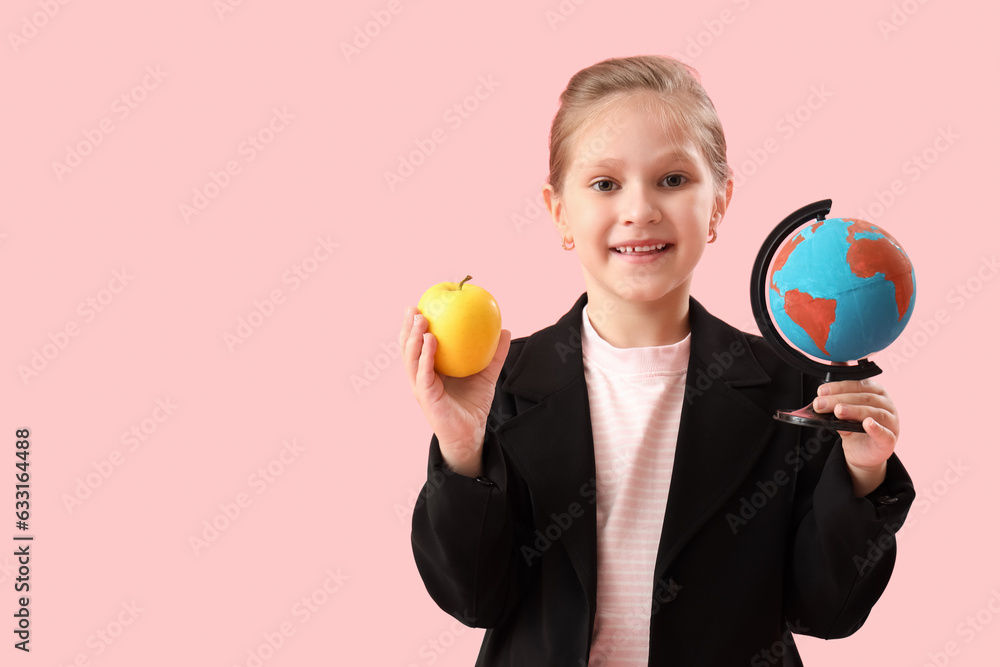 Little schoolgirl with globe and apple on pink background