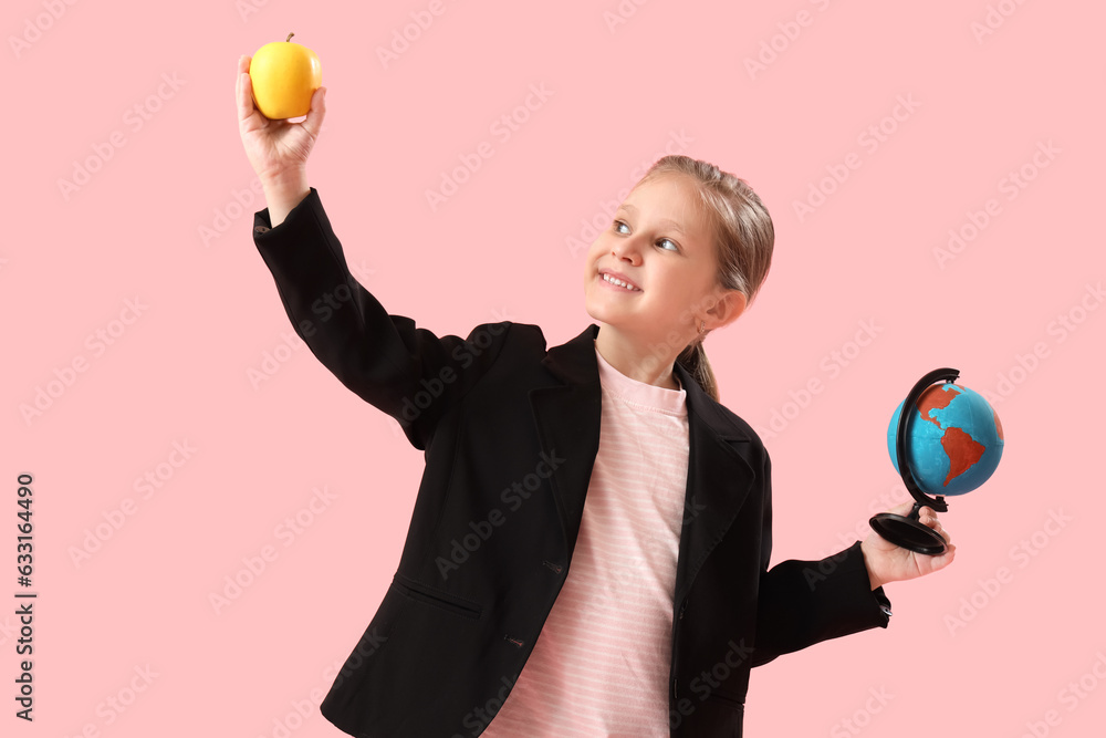 Little schoolgirl with globe and apple on pink background