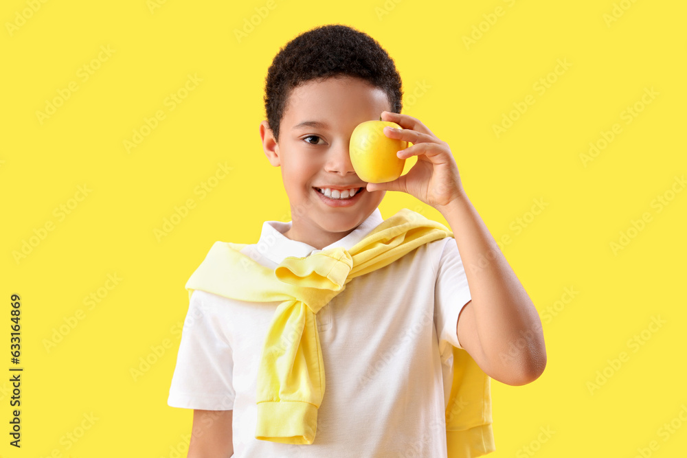 Little African-American boy with apple on yellow background