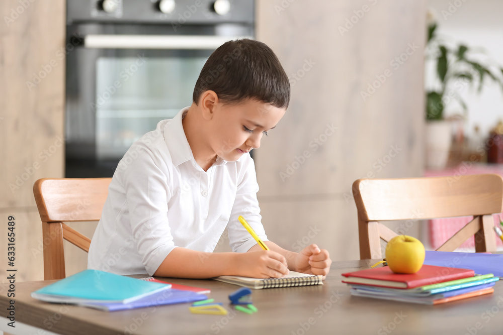 Cute little boy doing homework in kitchen