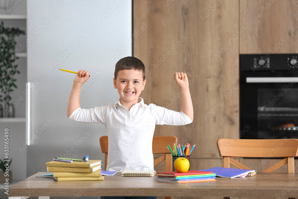 Cute little boy doing homework in kitchen