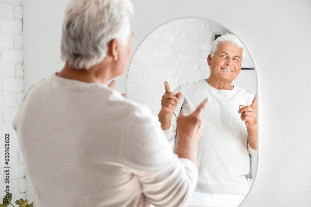 Senior man looking in mirror at home