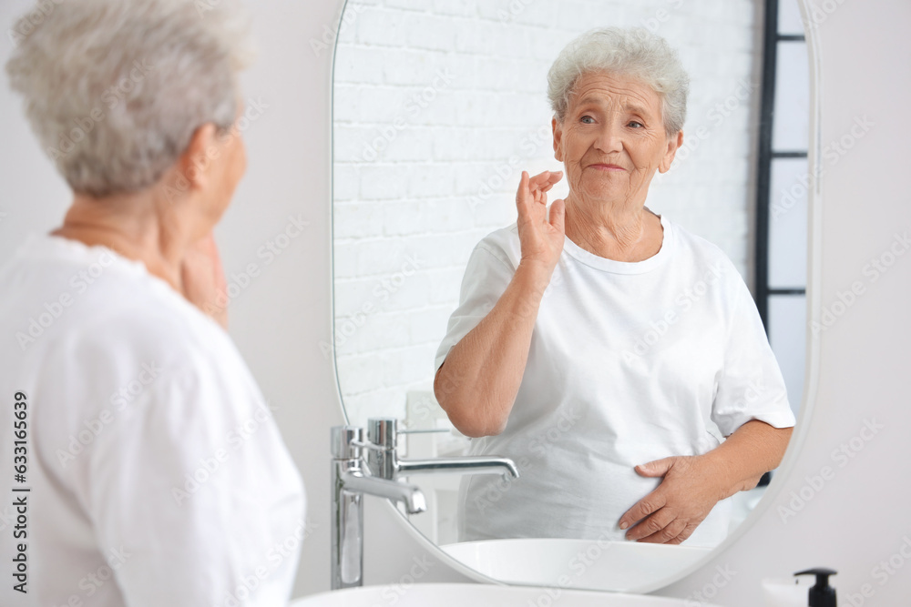 Senior woman looking in mirror at home