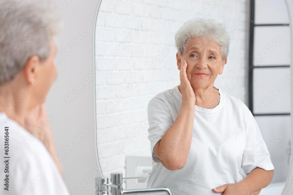 Senior woman looking in mirror at home