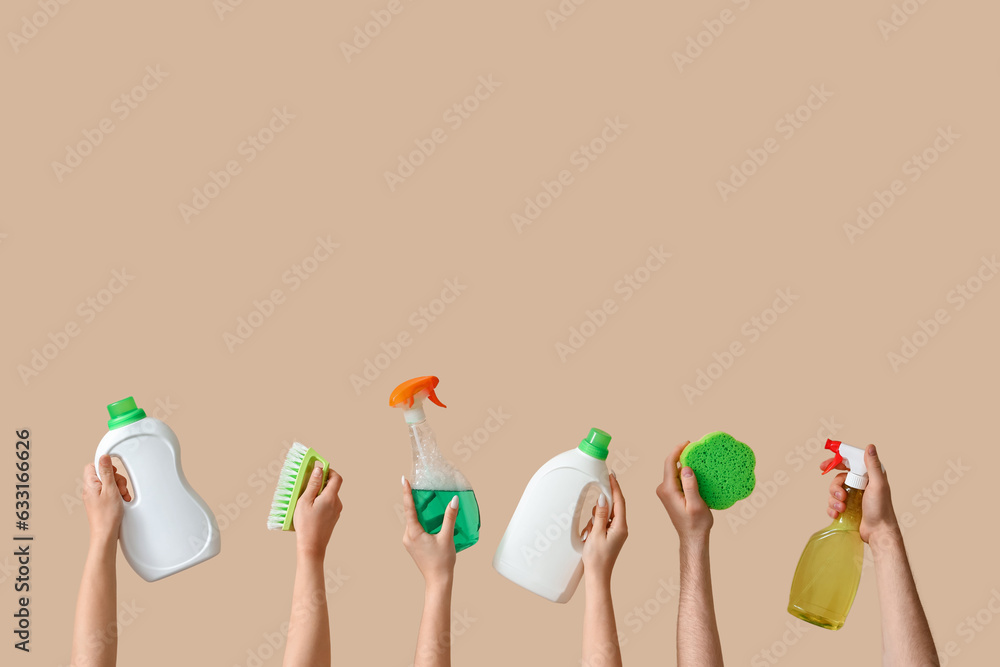 Women with cleaning supplies on beige background