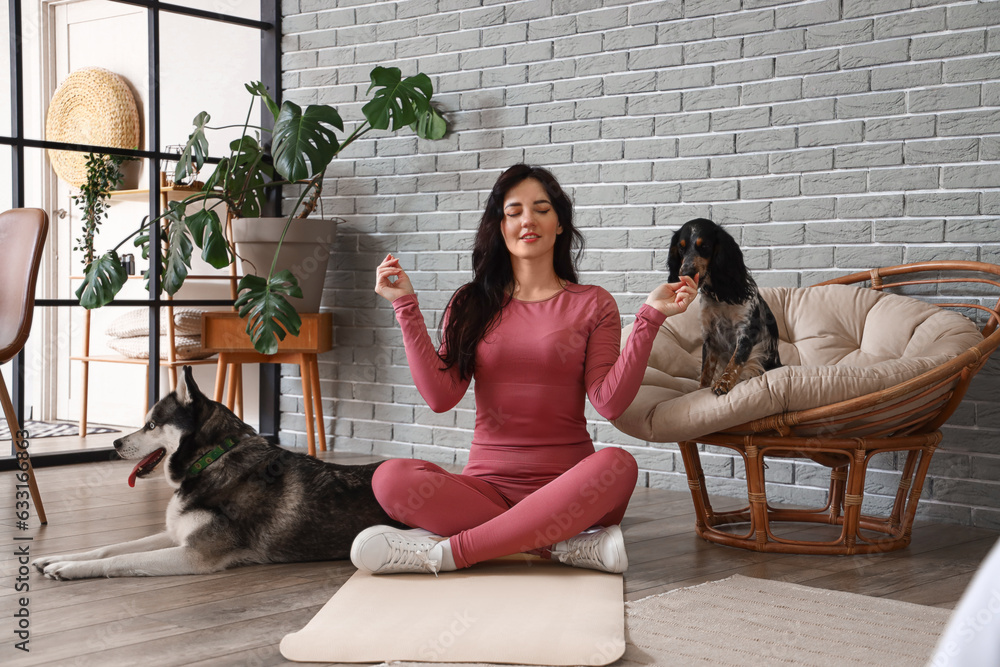 Sporty young woman with her dogs meditating at home