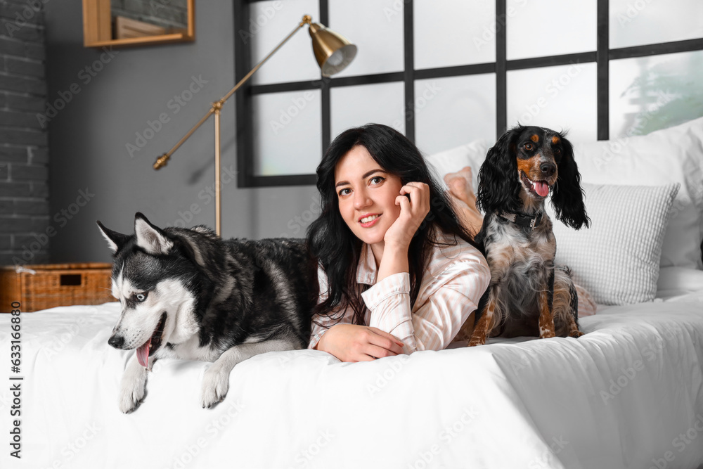 Young woman with cute dogs in bedroom