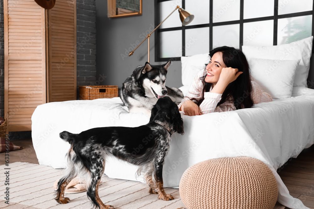 Young woman with cute dogs in bedroom