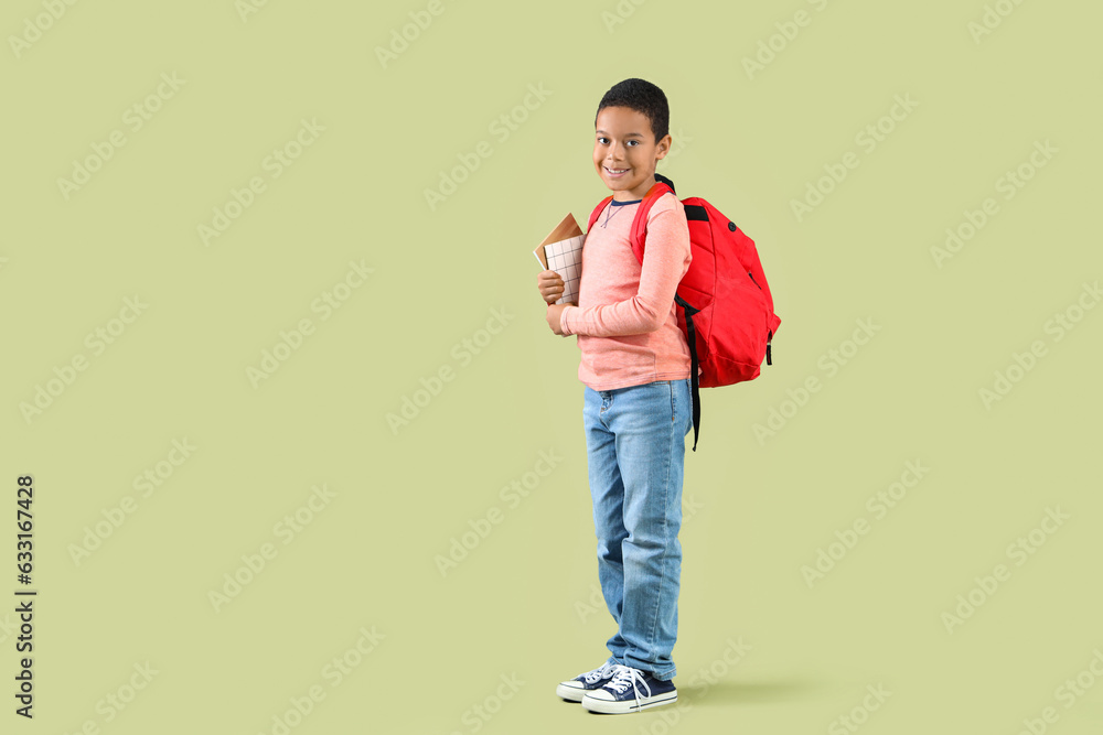 Little African-American boy with school backpack on green background