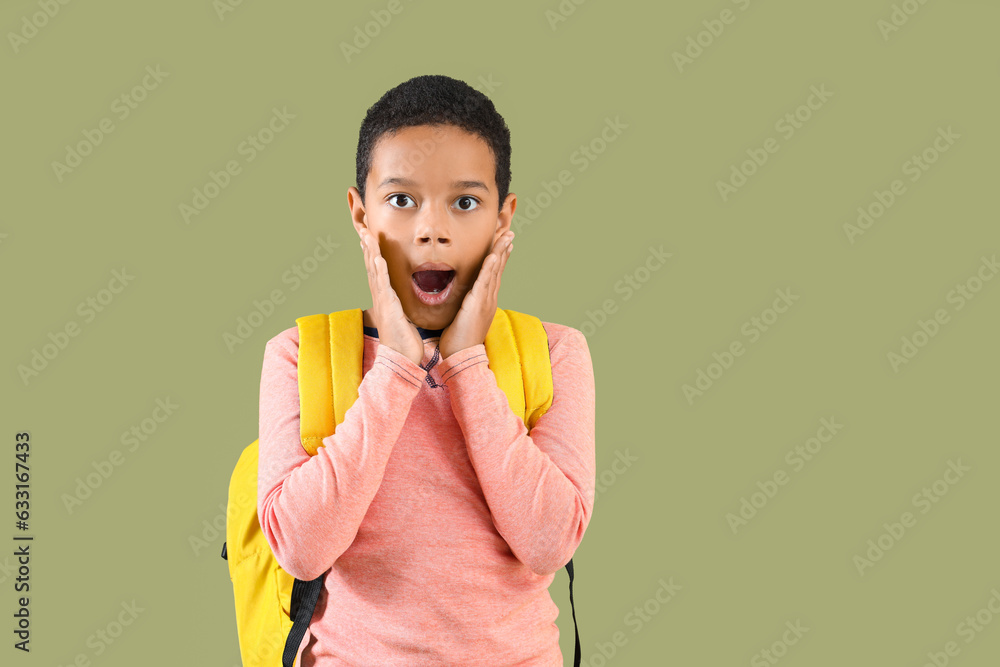 Surprised African-American boy with school backpack on green background