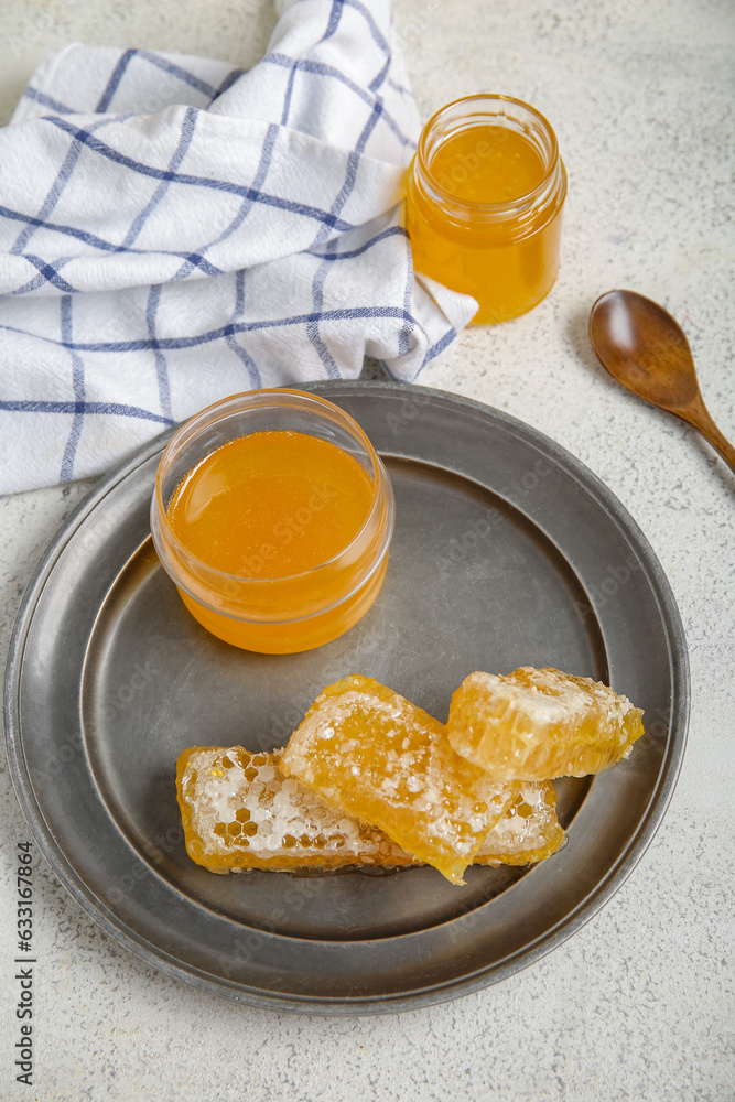 Plate with jar of sweet honey and combs on light background