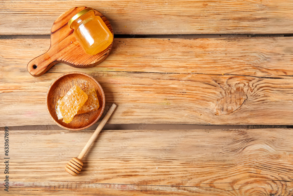 Jar of tasty honey, dipper and combs on wooden background