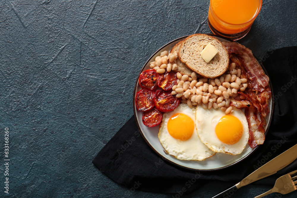 Plate with tasty English breakfast and glass of juice on black background