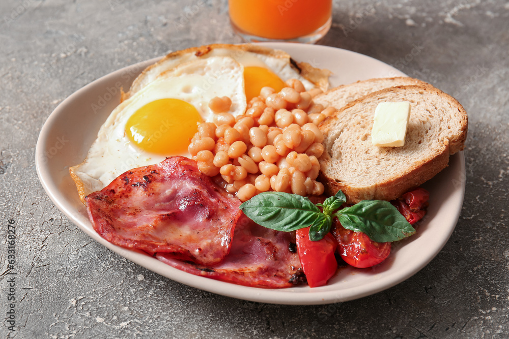 Plate of tasty English breakfast with fried eggs on grey background