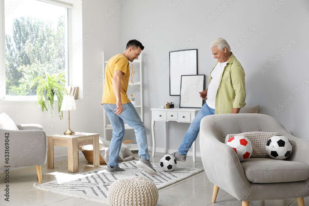 Young man with his father playing football at home